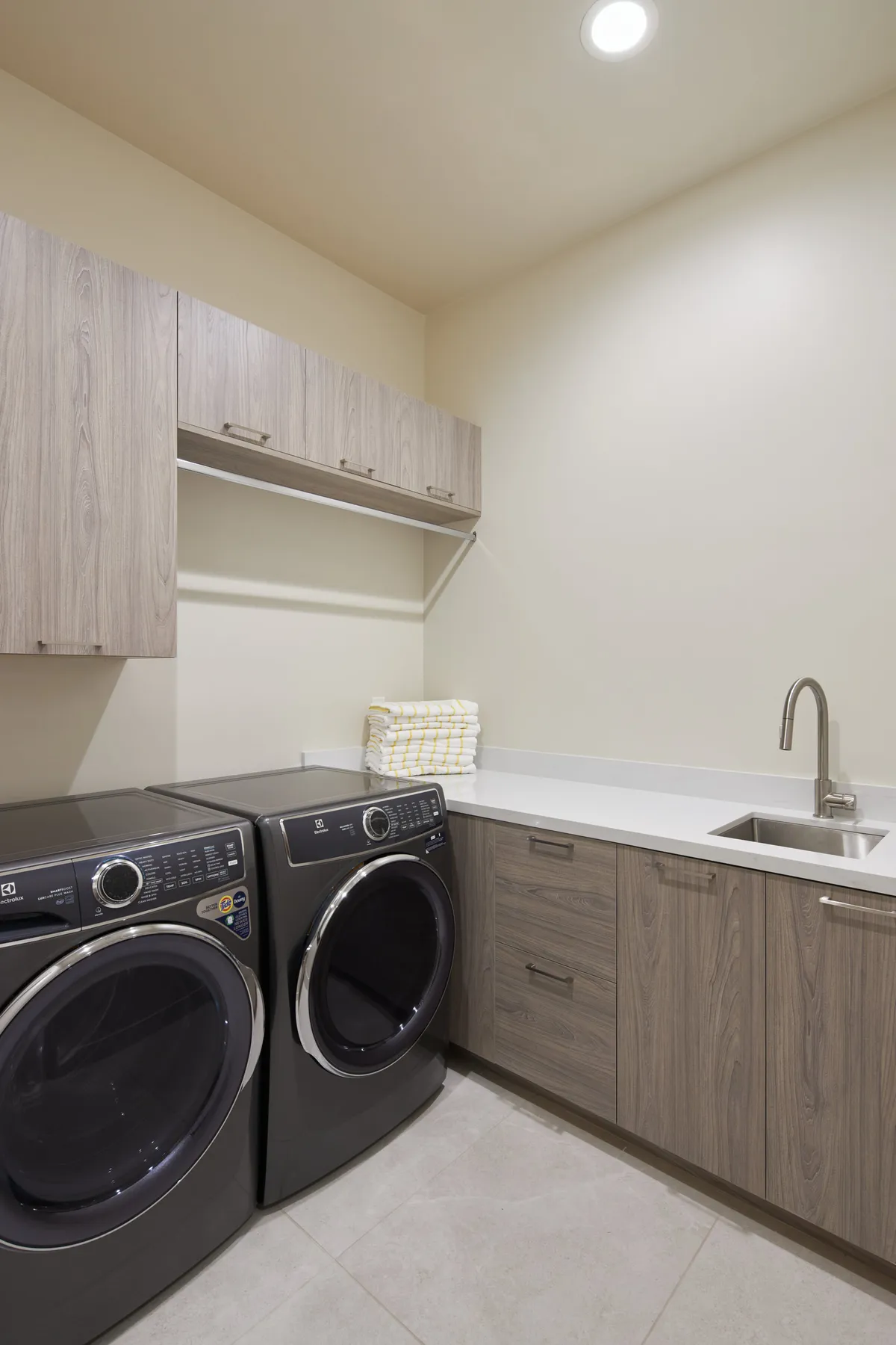 A functional laundry area featuring a modern washer and dryer, a spacious sink for handwashing, and plentiful storage cabinets. The space is bright, organized, and designed for convenience—reflecting attention to practical details that enhance guest comfort.