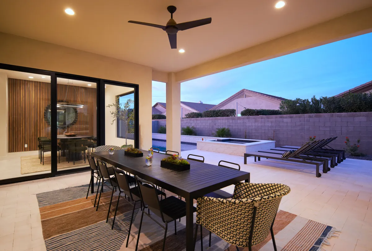 A spacious patio with a large dining table set for al fresco meals, seamlessly connecting to the pool area. Comfortable seating invites guests to relax and enjoy views of the water and landscaped grounds, ideal for group gatherings.