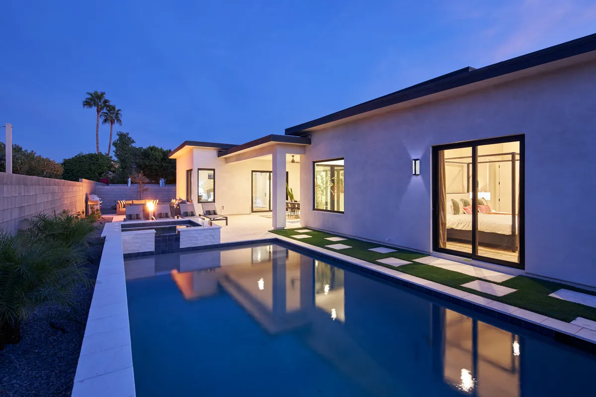 A luxurious backyard oasis featuring a sparkling swimming pool, a cozy fire pit with surrounding seating, and an inviting outdoor lounge area. Ambient lighting and sunset hues evoke relaxation and togetherness, ideal for unwinding after a day of adventure.
