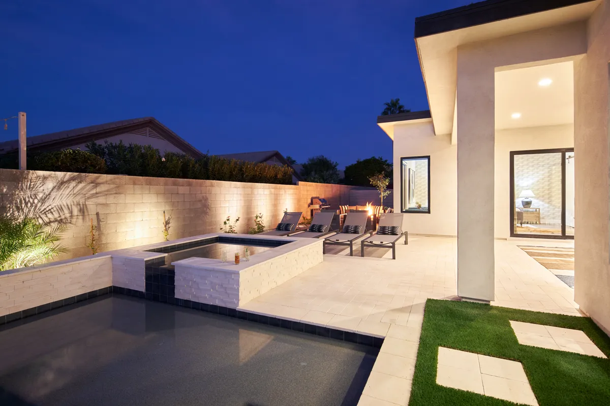 A tranquil pool and spa area bordered by plush lounge chairs and vibrant landscaping. The elevated hot tub and landscaped garden set a refined, sophisticated mood, inviting guests to relax and socialize.